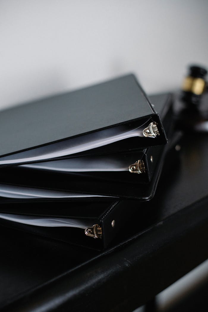 Stack of various black folders for documents on wooden table in modern office